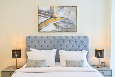 a bedroom with a bed and a painting on the wall at New Luxury 2 Bedroom with Burj Khalifa View & Spectacular Rooftop Infinity Pool Bar in Dubai