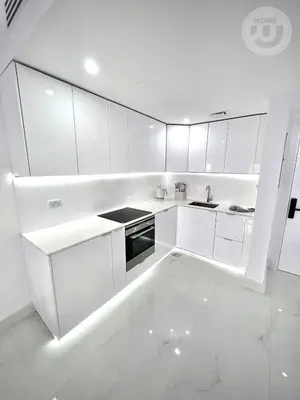a white kitchen with white cabinets and appliances at BRAND NEW luxury & modern in JLT in Dubai