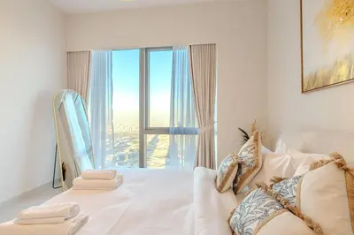 a bedroom with a white bed with a large window at 63rd High Floor - Full private Burj Khalifa and Fountain View - 2 Bedroom in Dubai