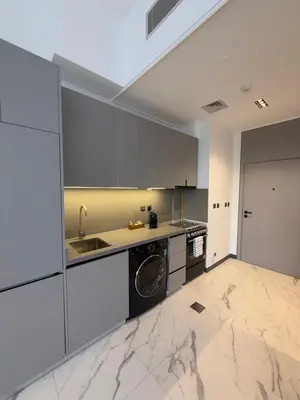 a kitchen with white cabinets and a washer and dryer at Cozy Dubai Studio I Prime Spot in Dubai