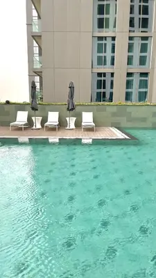 a group of chairs and umbrellas next to a pool of water at Premium Chic Fully Furnished 1 BR in Sobha Hartland in Dubai