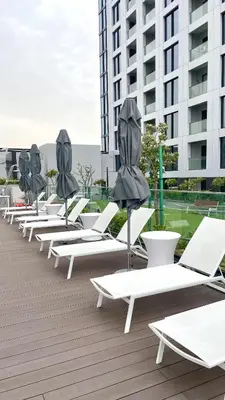 a row of lounge chairs and umbrellas on a roof at Premium Chic Fully Furnished 1 BR in Sobha Hartland in Dubai