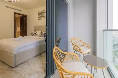 a bedroom with a bed and two chairs and a table at Premium Chic Fully Furnished 1 BR in Sobha Hartland in Dubai