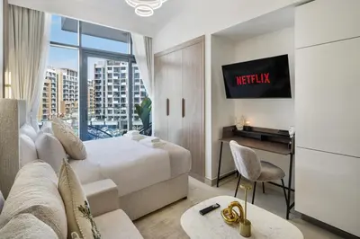 a bedroom with a bed and a desk with a tv at Modern Meydan Studio Near Dubai Mall & Downtown in Dubai