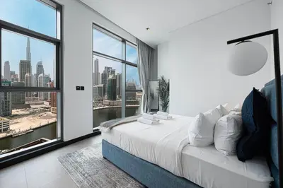 a bedroom with a bed and a large window at Luxury 2BR Burj Khalifa and Canal View Pool Jacuzzi in Dubai