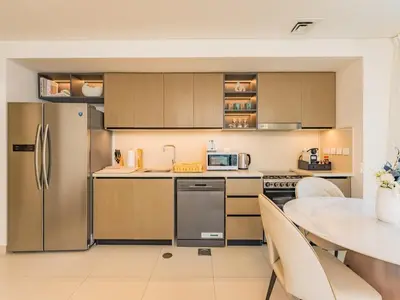 a kitchen with stainless steel appliances and a table at the 'Paris' Condo - Stylish 2Bd with Burj View in Dubai