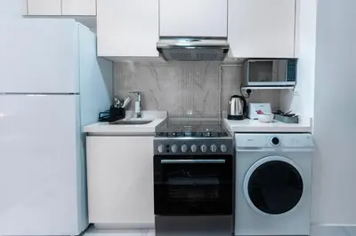 a kitchen with a stove and a washing machine at Vibrant Studio with Gym Access in Dubai