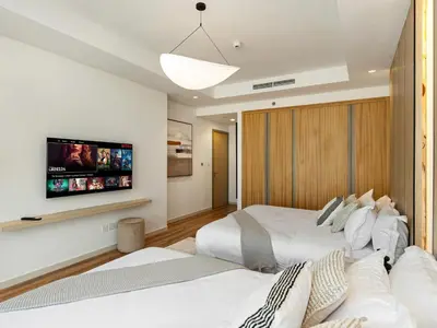 two beds in a bedroom with a tv on the wall at Burj View 3BDR with Rooftop Infinity Pool in Dubai