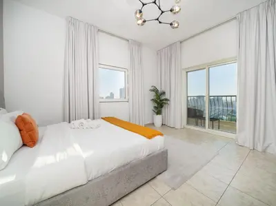 a white bedroom with a bed and large windows at Elegant and Spacious 2-Bedroom Apartment in JVT in Dubai