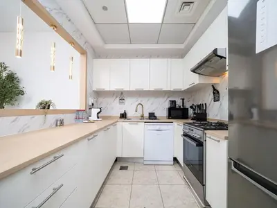 a kitchen with white cabinets and a sink at Elegant and Spacious 2-Bedroom Apartment in JVT in Dubai