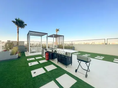 a backyard with a barbecue grill and grass at FIRST CLASS 1BR Stylish Urban Retreat in Dubai