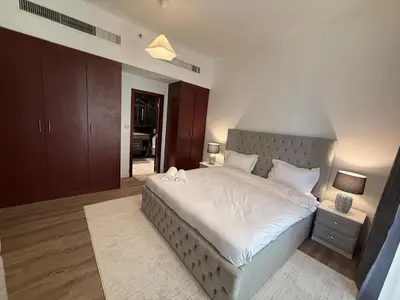 a bedroom with a large bed with white sheets at 1BR Apartment JBR in Dubai