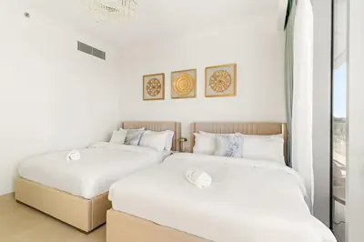 two beds in a room with white walls at Elegant 1BR Apt with Balcony Views of Burj Khalifa & Dubai Canal in Dubai