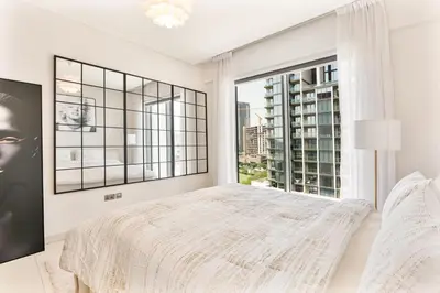 a bedroom with a bed and a large window at Luxury 2BR in Sobha Hartland in Dubai