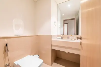 a bathroom with a toilet and a sink and a mirror at Luxury 4BR with Hermes Touch & Burj Khalifa View in Dubai