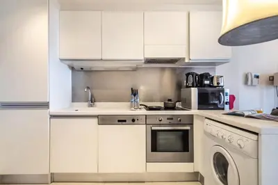 a kitchen with white cabinets and a sink and a microwave at Luxury Studio in Emaar Residence Fashion Avenue in Dubai