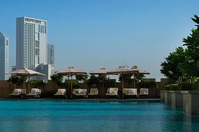 a swimming pool with chairs and umbrellas in a city at Luxury Studio in Emaar Residence Fashion Avenue in Dubai