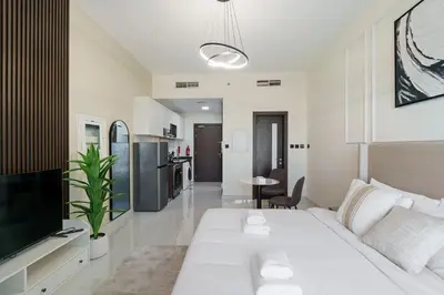 a white living room with a white couch and a tv at Modern Studio with all Amenities Ideal Location in Dubai