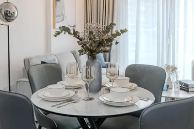 a dining room table with chairs and a vase with flowers at Clever Guest 029 Bella Rose in Dubai