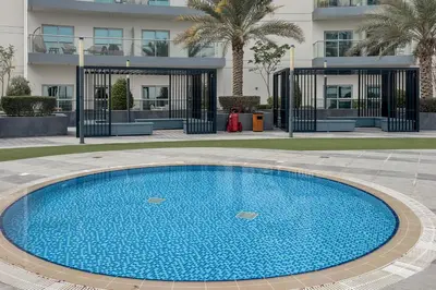 a large blue swimming pool in front of a building at Clever Guest 029 Bella Rose in Dubai