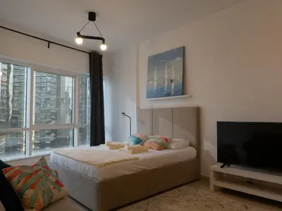 a bedroom with a bed and a flat screen tv at Bright studio with new furniture in Dubai