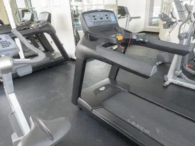 a gym with a treadmill and two tread machines at Bright studio with new furniture in Dubai