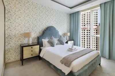 a bedroom with a large bed with a blue headboard at Luxury 4BR Apartment in JBR Private Beach Access in Dubai