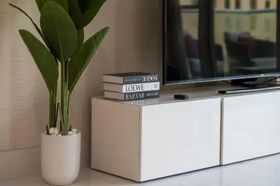 a white cabinet with a tv and a potted plant at Luxury 4BR Apartment in JBR Private Beach Access in Dubai
