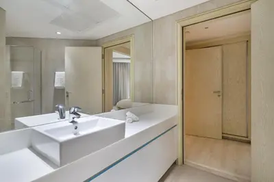 a white bathroom with a sink and a mirror at Luxury 4BR Apartment in JBR Private Beach Access in Dubai