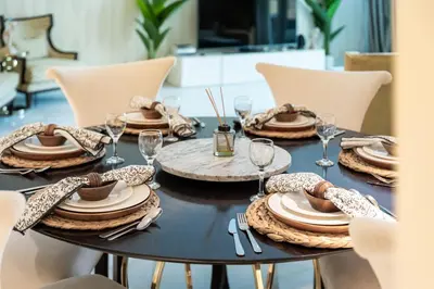 a black table with plates and wine glasses on it at Luxury 4BR Apartment in JBR Private Beach Access in Dubai