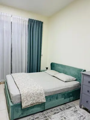 a bedroom with a green bed with a window at Spacious Studio in Dubai Sports City in Dubai