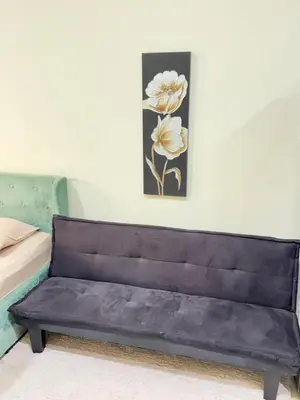 a black couch in a room with a painting on the wall at Spacious Studio in Dubai Sports City in Dubai