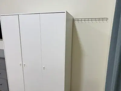 a closet with white cabinets and a blue curtain at Spacious Studio in Dubai Sports City in Dubai
