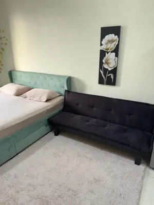 a bed with a bench in a room at Spacious Studio in Dubai Sports City in Dubai
