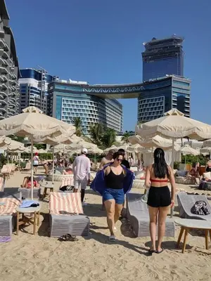 two women walking on a beach with umbrellas at 7 palm Jumeirah one bedroom in Dubai