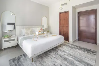 a white bedroom with a large bed with a mirror at Frank Porter - Beauport Tower in Dubai