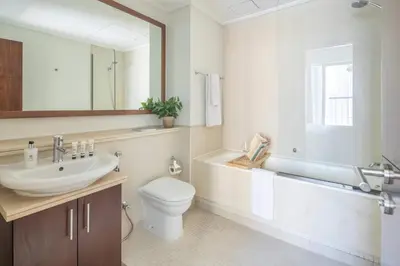 a bathroom with a sink and a toilet and a mirror at Frank Porter - Beauport Tower in Dubai