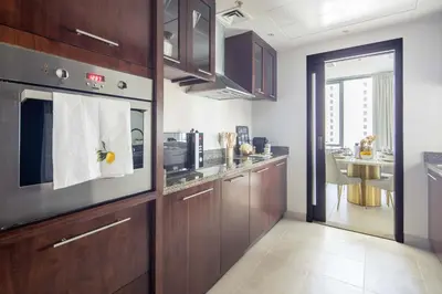 a kitchen with wooden cabinets and a dining room at Frank Porter - Beauport Tower in Dubai
