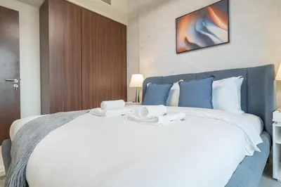 a bedroom with a large white bed with towels on it at Burj View - Chic 2BR - 5min Dubai mall Canal in Dubai