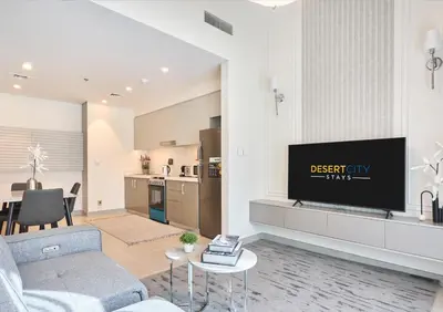 a living room with a couch and a tv and a kitchen at Cozy & Modern 1 Bedroom Apartment in Downtown Dubai, Hosted by Desert City Stays in Dubai