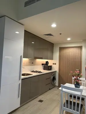 a kitchen with a white refrigerator and a table at Azizi riviera luxury studio apartment monthly rent in Dubai