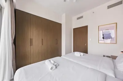 a bedroom with two beds with white sheets and wooden cabinets at Walk to Dubai Mall- Enjoy Burj Khalifa Show in Dubai
