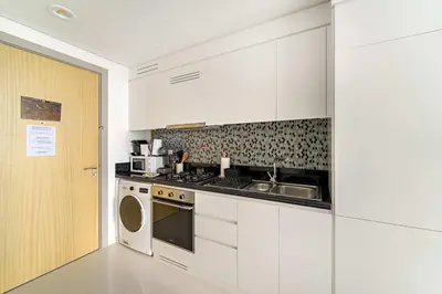 a white kitchen with a sink and a stove at Silkhaus Cozy Studio at Business Bay in Aykon City in Dubai