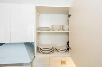 a cupboard with plates and bowls in it at Stylish Studio Bayz Danube Burj Khalifa View Pool in Dubai