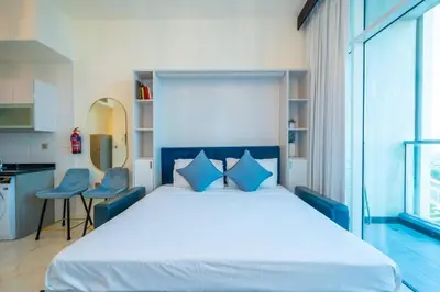 a bedroom with a large bed with blue pillows at Stylish Studio Bayz Danube Burj Khalifa View Pool in Dubai