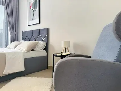 a bedroom with a bed and a chair and a table at Roomook Apartments in Dubai