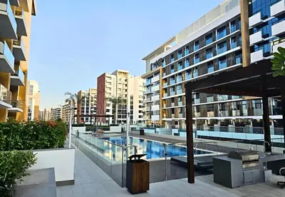a large building with a swimming pool in front of it at Roomook Apartments in Dubai