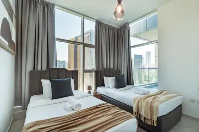 two beds in a room with large windows at Chic Waterfront Living - Marina View in Dubai