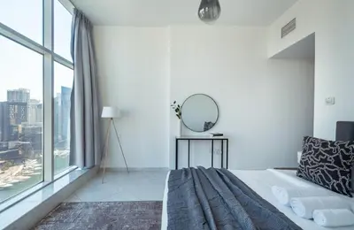 a white room with a bed and a mirror at Chic Waterfront Living - Marina View in Dubai