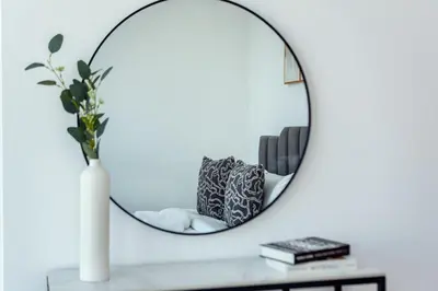 a mirror on a table with a vase and books at Chic Waterfront Living - Marina View in Dubai